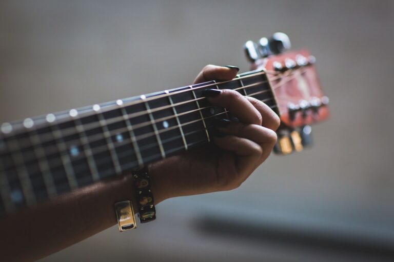 Finger greifen einen offenen Akkord am Griffbrett einer Akustikgitarre
