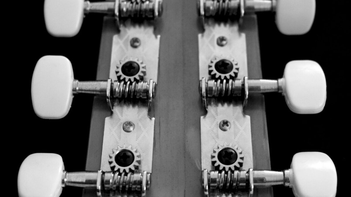 Hand stimmt die Saiten am Kopf einer Akustikgitarre