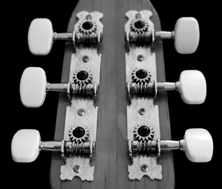 Hand stimmt die Saiten am Kopf einer Akustikgitarre