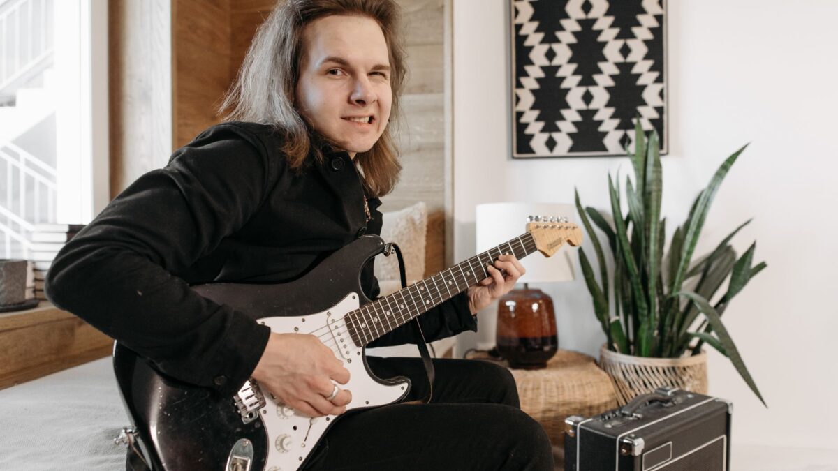Anfänger übt E-Gitarre vor einem kleinen Verstärker