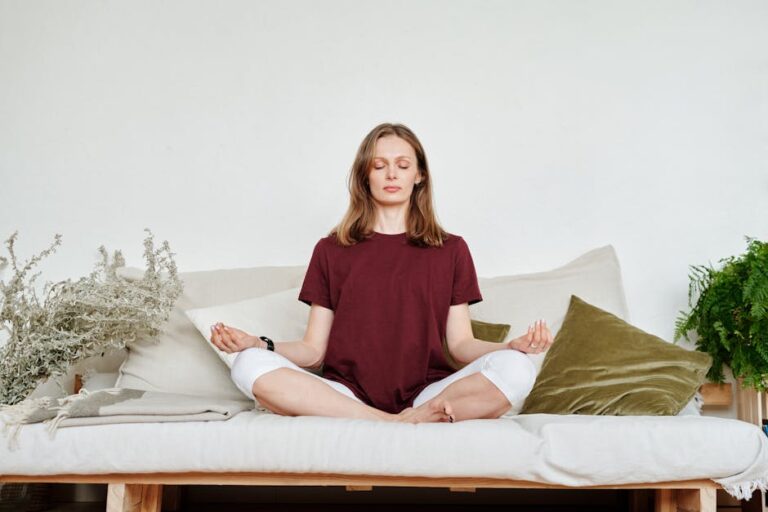 lento - Woman meditating indoors on a sofa, exuding calmness and mindfulness, surrounded by greenery