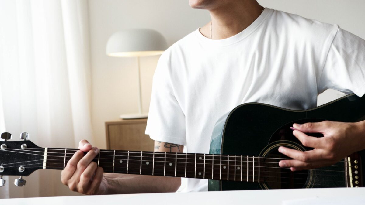 Anfänger übt Akkorde auf einer Akustikgitarre