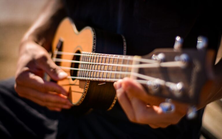 Hände greifen einen Akkord auf einer Ukulele